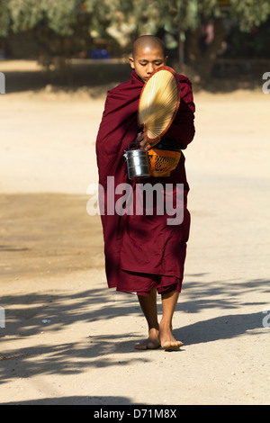 Monaco novizio con ventilatore, lunchbox e recipiente di raccolta a Bagan, Myanmar 2 Foto Stock