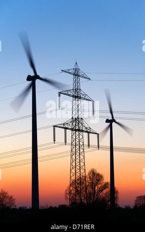 Alta tensione e montante di turbine eoliche al tramonto in Amburgo, Germania, Europa Foto Stock