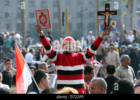 Un uomo egiziano trattiene il santo Corano e una Bibbia cristiana con la croce di legno durante un raduno di massa in piazza Tahrir al Cairo, Egitto Foto Stock