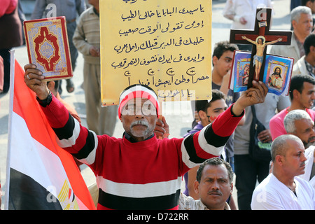 Un uomo egiziano trattiene il santo Corano e una Bibbia cristiana con la croce di legno durante un raduno di massa in piazza Tahrir al Cairo, Egitto Foto Stock