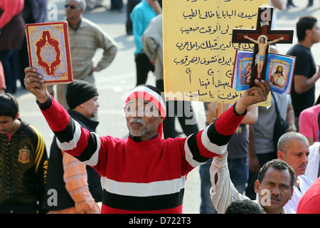 Un uomo egiziano trattiene il santo Corano e una Bibbia cristiana con la croce di legno durante un raduno di massa in piazza Tahrir al Cairo, Egitto Foto Stock