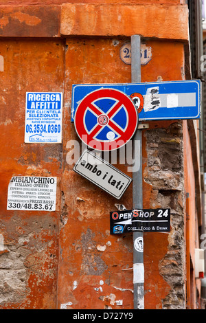 Segnaletica stradale e bill adesivi poster su un angolo di strada in Roma, Italia Foto Stock