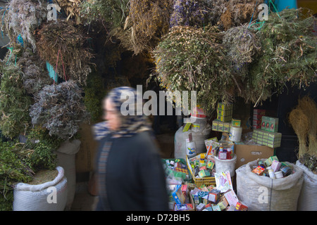 La donna passa dal negozio di vendita erbe sul Market street nella vecchia medina (Patrimonio Mondiale dell'UNESCO), Tunisi, Tunisia Foto Stock