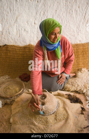 Donna macinazione del grano in abitazioni troglodite (case costruite nel sottosuolo), Matmata, Tunisia Foto Stock