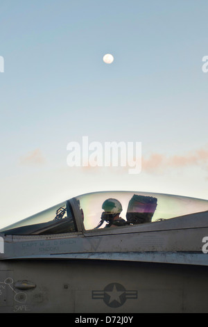 Un US Navy F/A-18C Hornet pilota da caccia si prepara a prendere il via in serata durante le operazioni di volo sulla portaerei USS Nimitz Aprile 23, 2013 nell'Oceano Pacifico. Foto Stock
