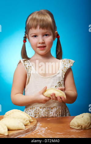 Sorridente bambina gli impasti in cucina con la cottura di un grafico a torta Foto Stock