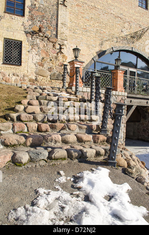 Stone cobbly scala con ringhiera in acciaio e la luce della lampada a leader retrò manor e neve rimangono in primavera. Foto Stock