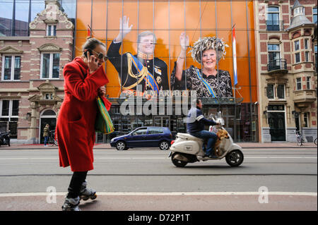 Paesi Bassi, Amsterdam, 27 Aprile 2013.Una giovane donna su pattini a rotelle passa da ritratti della Regina Beatrice dei Paesi Bassi e di suo figlio, il principe Willem-Alexander, visualizzato nella parte anteriore di un teatro in Amsterdam, Sabato 27 Aprile, 2013. Nei Paesi Bassi si sta preparando per la Festa della Regina il 30 aprile, che segnerà inoltre l'abdicazione della regina Beatrix e l' investitura del suo figlio primogenito Willem-Alexander. Alamy Live News Foto Stock