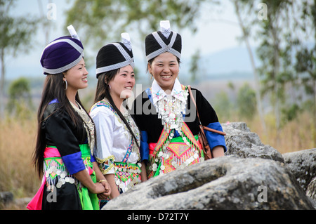 PHONSAVAN, Laos — tre giovani donne Hmong in costumi tradizionali per il Capodanno Hmong posa per una foto tra le antiche giare di pietra della piana di Jars, Laos. Foto Stock