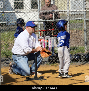 Piccola sfera a t t-ball giocatore di baseball alla piastra con il suo allenatore. Foto Stock