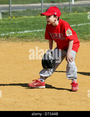 Un baseball Little League terzo baseman con le mani sulle ginocchia. Foto Stock