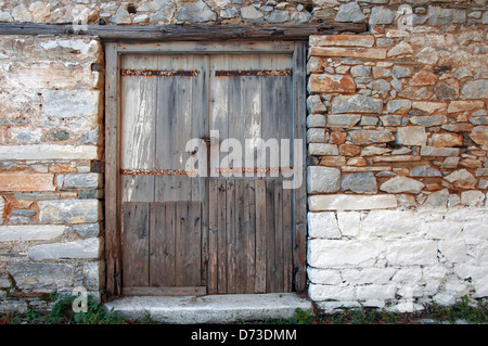 Sgangherate porta di legno nella vecchia casa di pietra anteriore (Grecia) Foto Stock