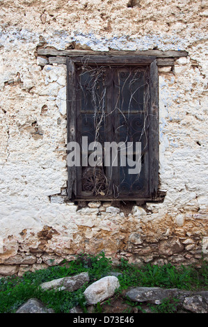 Vecchia finestra con ornati in griglia di ferro in weathered stone house parte anteriore Foto Stock
