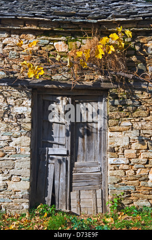 Sgangherate porta di legno nella vecchia casa di pietra parte anteriore Foto Stock