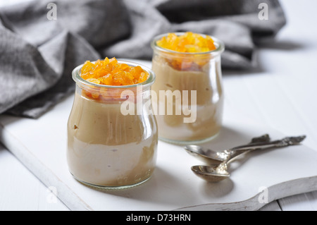 Budino al caramello con albicocche secche in vasetti di vetro su sfondo di legno Foto Stock