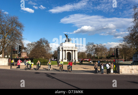 Ciclisti e pedoni in attesa di attraversare la strada a un semaforo, Hyde Park Corner, Londra, Inghilterra, Regno Unito. Foto Stock