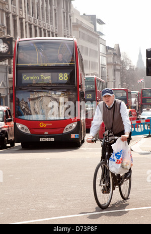 Un ciclista maschile in bicicletta a Piccadilly Circus con autobus e traffico di Londra, Central London W1, Regno Unito Foto Stock