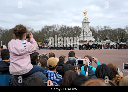 I turisti scattano fotografie utilizzando telecamere i telefoni cellulari e i computer tablet del Cambio della Guardia a Buckingham Palace Foto Stock