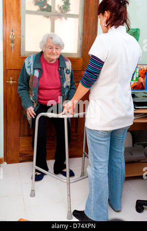 Sessione di fisioterapia in casa di una donna anziana a seguito di frattura. Foto Stock