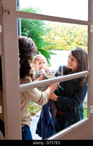 Una madre ha il suo mese 18 old Baby girl per un bambino caregiver. Foto Stock