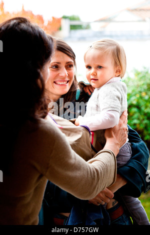 Una madre ha il suo mese 18 old Baby girl per un bambino caregiver. Foto Stock