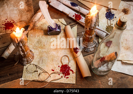 Tavolo antico riempito con vecchi giornali, sigillante rosso e candele Foto Stock