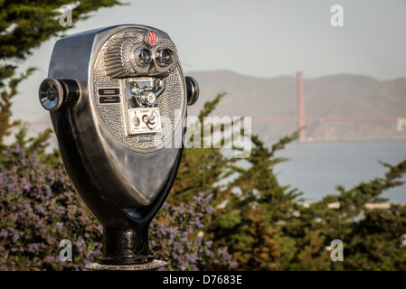 Coit Tower Lookout Binoculars Golden Gate Bridge San Francisco California // SAN FRANCISCO, California - binocolo Lookout posizionato presso Coit Tower su Telegraph Hill offrono vedute verso il Golden Gate Bridge. La torre fu costruita nel 1933 da fondi lasciati in eredità da Lillie Hitchcock Coit, una socialite e filantropa di San Francisco che lasciò soldi alla città per progetti di abbellimento. La Coit Tower è alta 210 metri e serve sia come punto di riferimento che come punto di osservazione affacciato sulla Baia di San Francisco e sulla città. La struttura Art Deco ospita murales dipinti da artisti locali durante la depressione Foto Stock