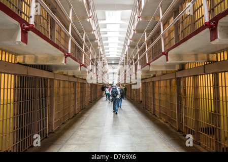 Alcatraz Federal Penitentiary Cell Block Interior San Francisco California | ALCATRAZ ISLAND, California - file di cellule a più livelli si estendono lungo il blocco di celle del Penitenziario Federale di Alcatraz mentre i visitatori camminano lungo il corridoio centrale una volta pattugliati dalle guardie. La prigione di massima sicurezza operò dal 1934 al 1963 e detenne famigerati detenuti come al Capone. La Golden Gate National Recreation area ora conserva il sito sotto il National Park Service. Foto Stock