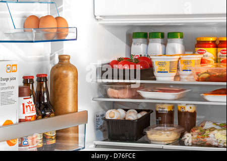 Si raffredda il cibo e le bevande in frigo aperta / frigorifero in cucina Foto Stock