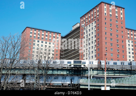 A New York City metropolitana treno su una elevata via passa in un edificio di appartamenti a Coney Island, Brooklyn, New York City Foto Stock