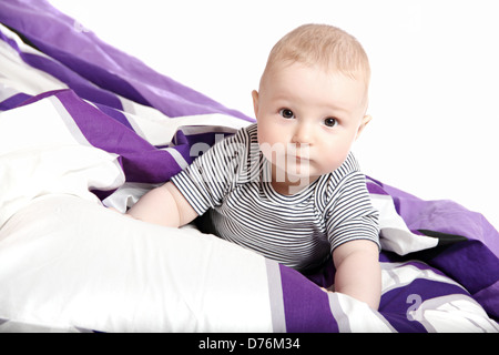 Bambino sul letto sotto coperta Foto Stock