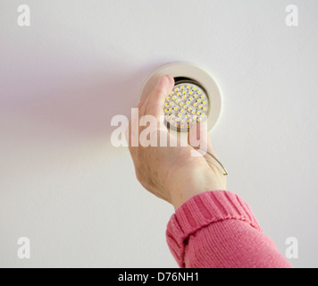 Regno Unito donna anziana mettendo in un soffitto LED lampadina a risparmio di energia Foto Stock