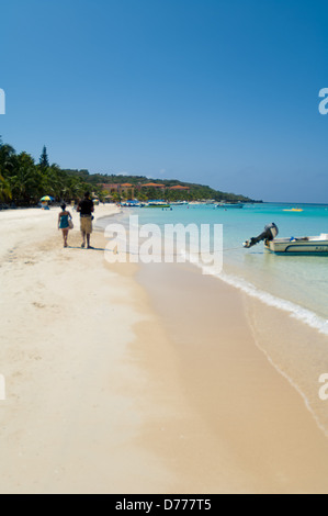I turisti a languire su una soleggiata spiaggia tropicale mentre è in vacanza nell'Isola di Roatan, Honduras. Foto Stock