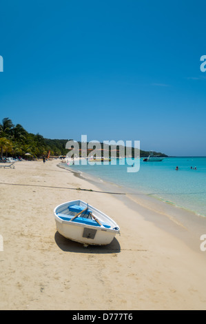 I turisti a languire su una soleggiata spiaggia tropicale mentre è in vacanza nell'Isola di Roatan, Honduras. Foto Stock