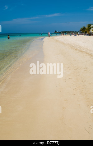 I turisti a languire su una soleggiata spiaggia tropicale sull'isola di Raotan, Honduras. Foto Stock