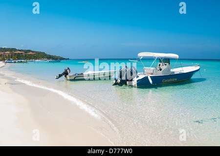 I turisti a languire su una soleggiata spiaggia tropicale mentre è in vacanza nell'Isola di Roatan, Honduras. Foto Stock