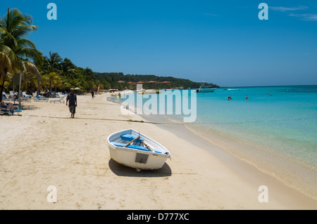 I turisti a languire su una soleggiata spiaggia tropicale mentre è in vacanza nell'Isola di Roatan, Honduras. Foto Stock
