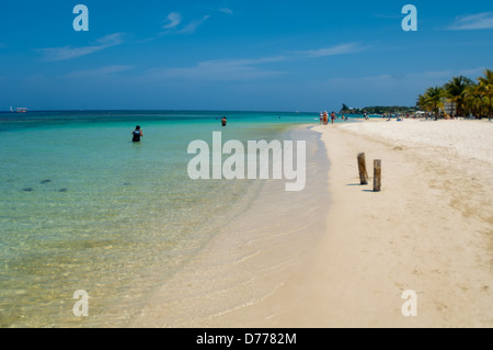 I turisti a languire su una soleggiata spiaggia tropicale sull'isola di Raotan, Honduras. Foto Stock