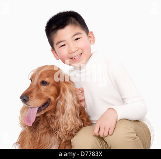 Ritratto di ragazzo seduto accanto al suo cane, studio shot Foto Stock