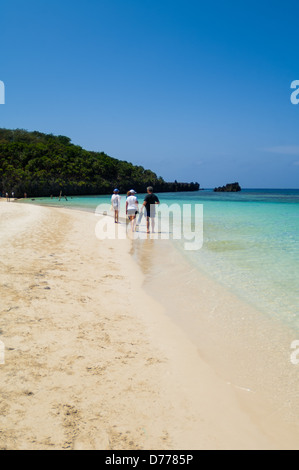 I turisti a languire su una soleggiata spiaggia tropicale mentre è in vacanza nell'Isola di Roatan, Honduras. Foto Stock
