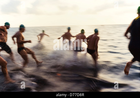 Inizio di Ironman Triatalon, concorrenti in esecuzione in oceano, effetti di movimento e splash. Foto Stock