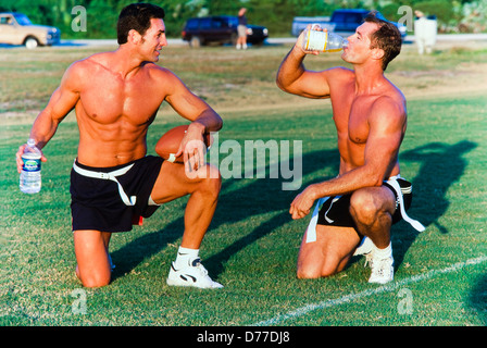 Gli uomini che giocano a calcio, teamates idratante, team competition, soleggiato pomeriggio di gioco. Foto Stock