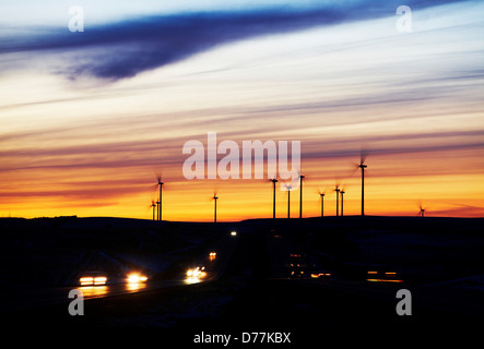 Stati Uniti Kansas luci di striature di macchine passando sulla Interstate Highway sagome distanti Wind Turbine wind farm al crepuscolo Foto Stock