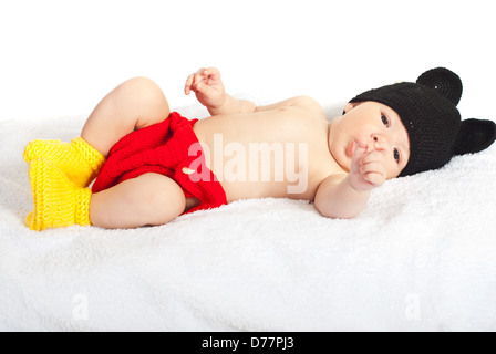 Neonato ragazzo posa su un soffice coltre in maglia costume colorato Foto Stock