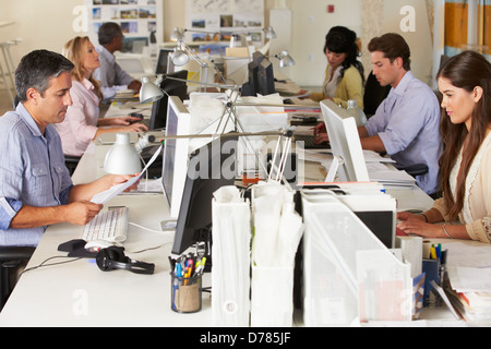 Team di lavoro alla scrivania in ufficio occupato Foto Stock