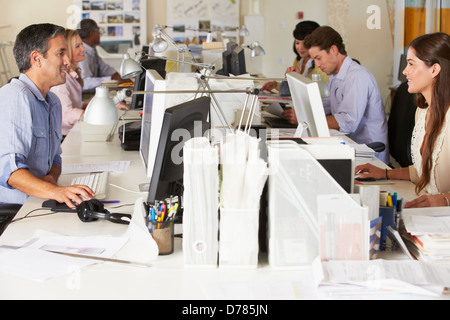 Team di lavoro alla scrivania in ufficio occupato Foto Stock