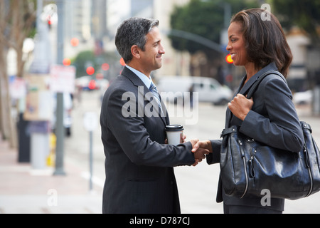 Imprenditore e imprenditrice stringono le mani in strada Foto Stock