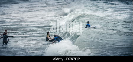 Sconsiderato crazy mad surfers nel congelamento mare tempestoso acqua a Bigbury Bay Burgh isola Devon England panorama 2.35:1 Foto Stock