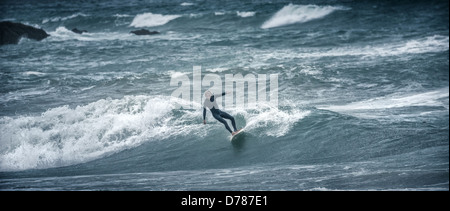 Sconsiderato crazy mad surfers nel congelamento mare tempestoso acqua a Bigbury Bay Burgh isola Devon England panorama 2.35:1 Foto Stock