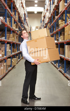 Uomo che trasportava scatole in magazzino Foto Stock